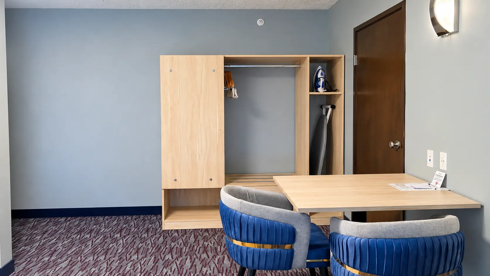 Open closet with hangers, iron and ironing board beside a table and chairs — Best Western Vernal Inn, Vernal Utah